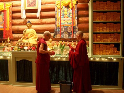 Venerables Semkye and Chonyi preparing offerings in front of the Abbey altar.