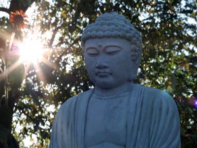 Statue of a Buddha in front of a setting sun.