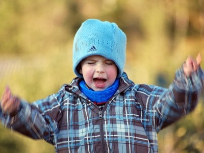 An angry young boy, appearing to be shouting.