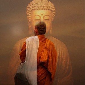 A monk standing in front of a Buddha statue.