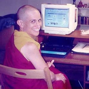 Venerable Chodron sitting at her computer, smiling.