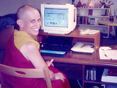 Venerable Chodron sitting at her computer desk, smiling.