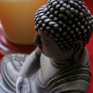 Small Buddha statue next to a candle.