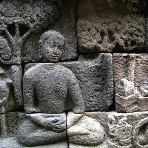 Stone sculpture of monk meditating near Chaityas.