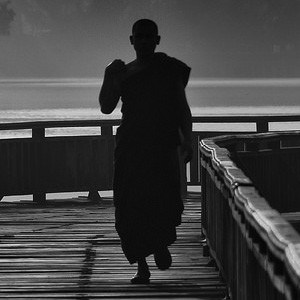 Silhouette of monk walking outside.