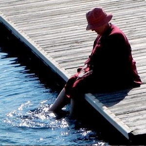 Venerable Jigme sitting on a lake dock with her feet in the water.