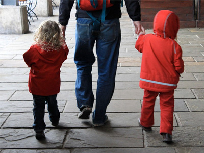 Father walking hand-in-hand with two children.