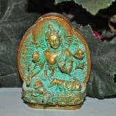 Green Tara tsa tsa with gold trim in front of leaves.