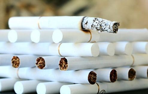 Cigarettes stacked neatly with the top one burning