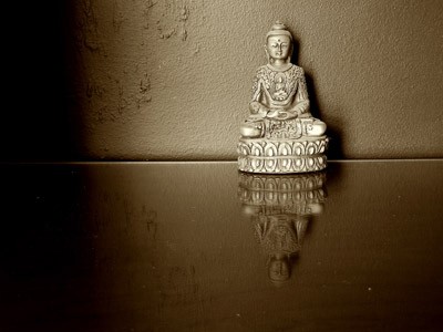 A buddha statue with reflecting image of the buddha on the surface.