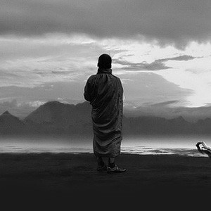 Silhouette of monastic standing on beach.