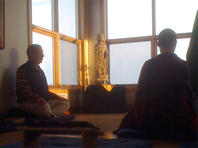A monastic and lay practitioner meditating together.