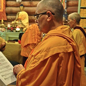 Venerable Yeshe recicting verses with a prayer book.