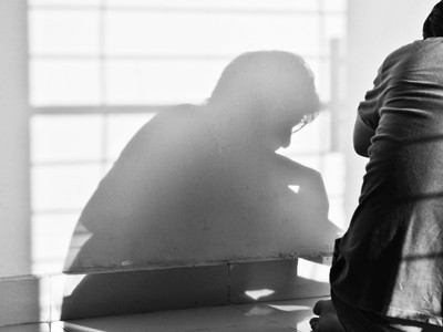 The shadow of a man sitting on the floor and shadows of window grills.