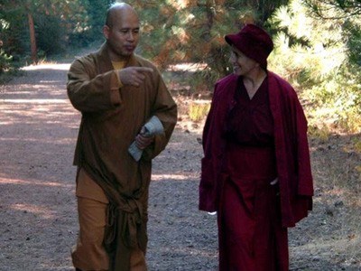 Venerable Chodron and a monk walking down a path, in conversation.