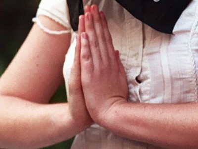 A young woman with palms together.