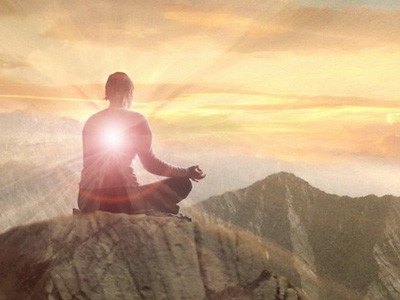 A person sitting on top of a moutain, meditating.