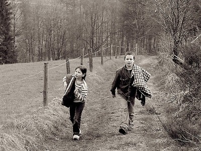 Brother and sister walking together down country road.