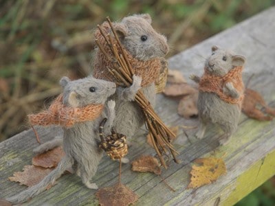 3 stuffed mice-One bigger mice taking sticks, one smaller mice taking a basket and one small mice looking at the big one carrying the sticks.