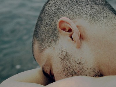 Man with head resting on folded arms.