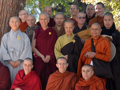 A group of nuns standing together under a tree.