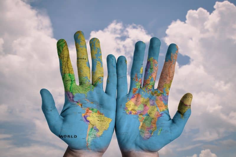 Two open hands with the map of Earth painted on them.