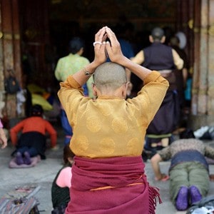 A nun putting her hands on the crown of her head doing prostration