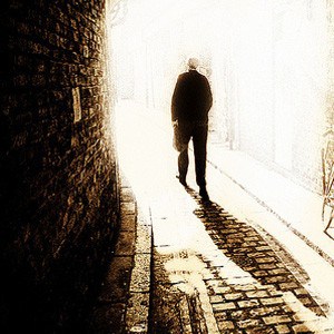 Man walking out of a tunnel toward light.