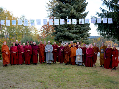Monastics standing under prayer flags at Sravasti Abbey.