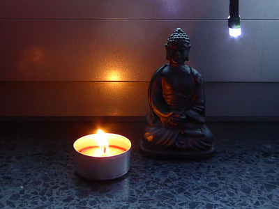 Candle by a Buddha statue.