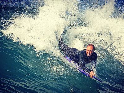 Man on a boogie board, riding a wave.