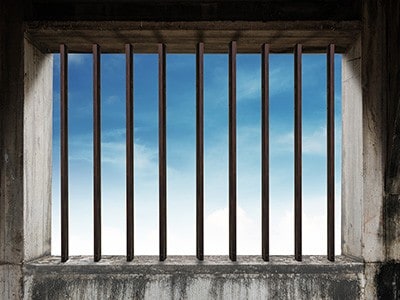 Looking through prison bars to blue sky outside.