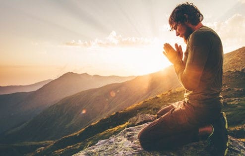 Young man praying at sunset.