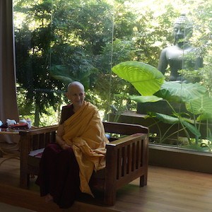 Venerable teaching in front of a large Buddha statue.