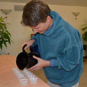 Heather pouring water into water bowls from a pitcher.