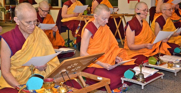 Venerable Chodron and other Abbey monastics sitting on meditation cushions and reading a text.