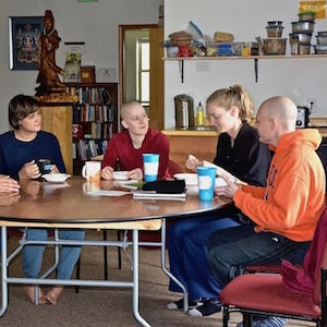 A group of young adults sitting at a table discussing teachings.