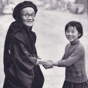 Elderly man and young child holding hands and smiling.