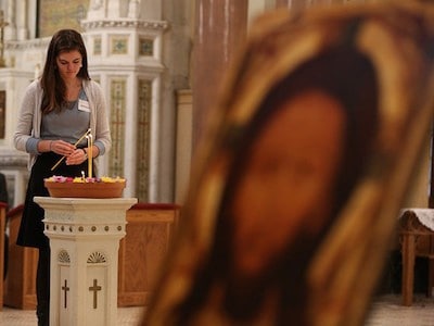 Woman lighting a candle during Catholic mass.