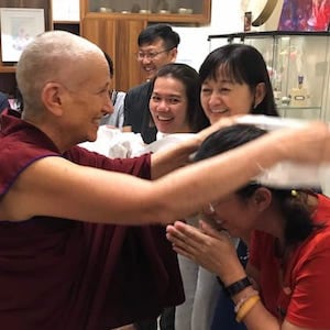 Venerable Chodron placing a khata around someone's neck.