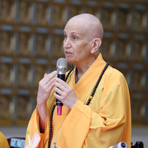 Venerable holding a microphone and speaking.