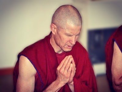 Monk with palms together, reciting prayers.