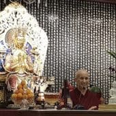 Venerable teaching in front of a large Buddha statue.