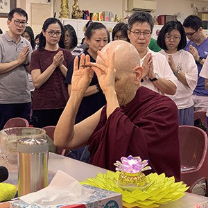 Venerable with hands raised, making an incense offering before teaching.