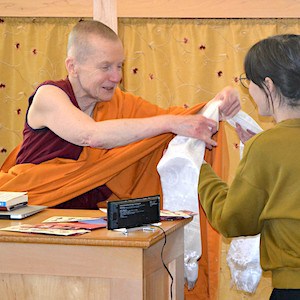 Ven. Sangye Khadro smiling while returning a white khata to a student.