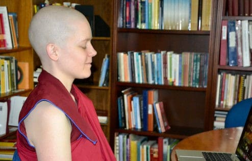 Nun smiling while meditating in a library.