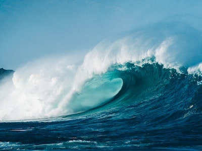 Foamy wave rolling over azure sea surface.