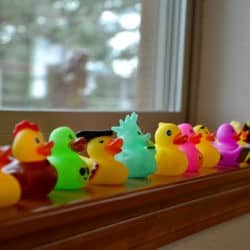 A row of rubber ducks on a windowsill.