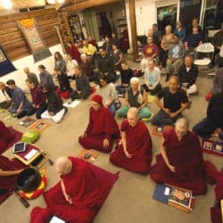 Bird's eye view of the Sravasti Abbey Meditation Hall filled with people meditating.