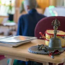 Prayer book, dorje, bell, and damaru on a wooden table.